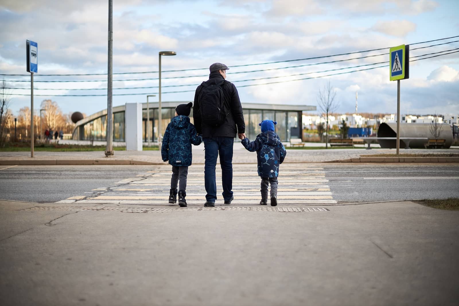 Parent with their two kids looking at the road before crossing the street