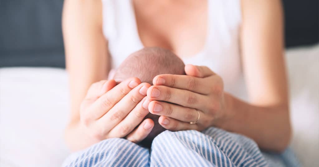 Mother Holding the Head of Her Newborn Baby Photo of Mother Holding the Head of Her Newborn Baby