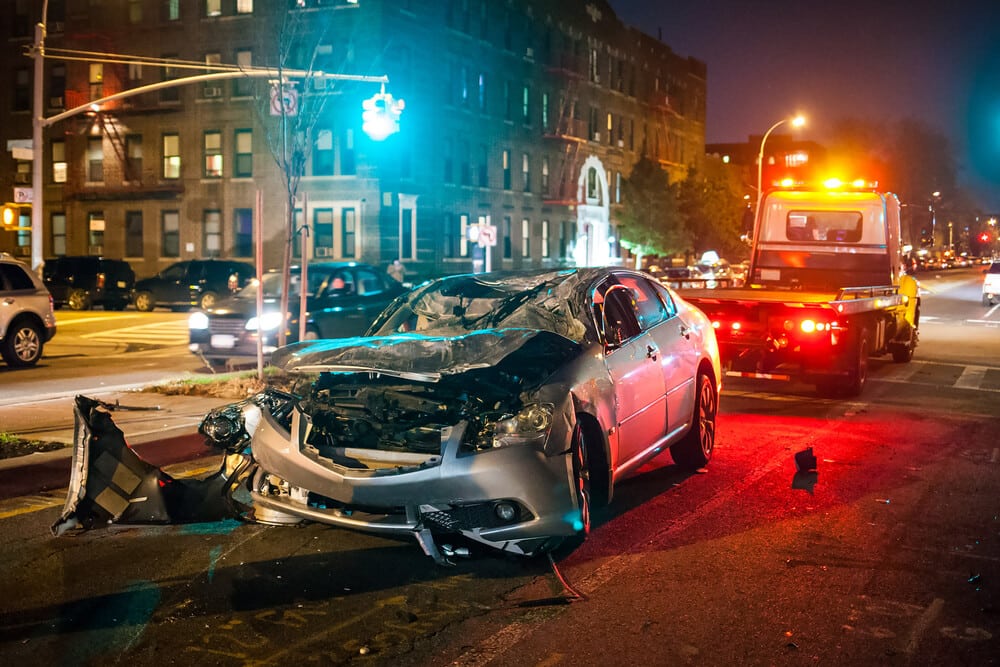 Totalled car at night getting towed
