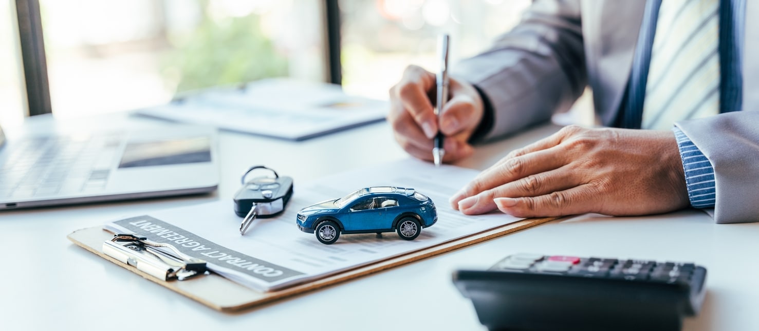 Man Signing Documents With Small Toy Car Over It