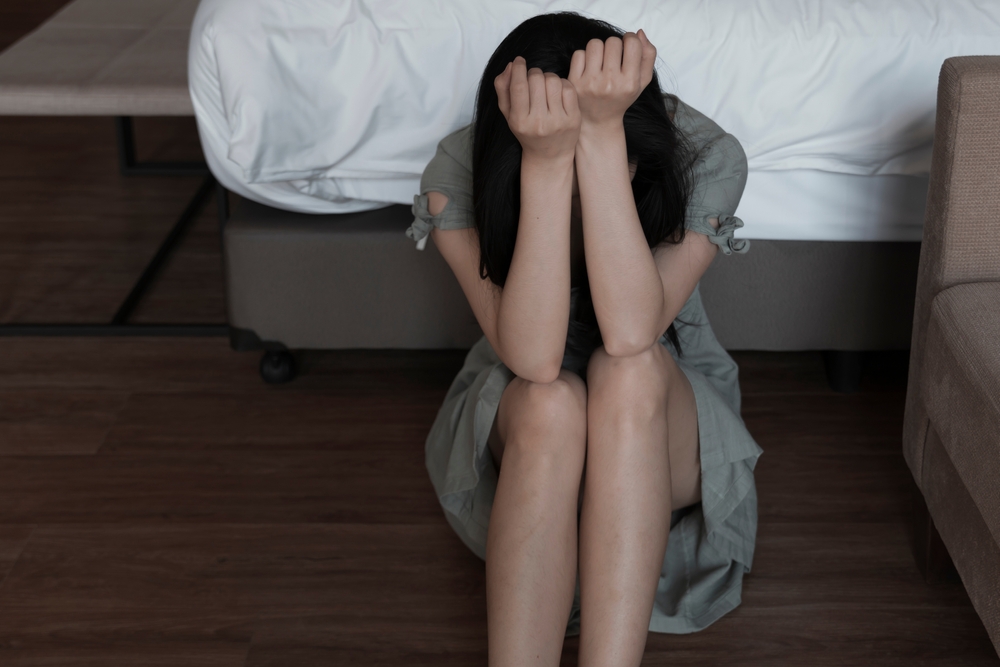Abused Woman Woman sitting on the floor with her head down and arms covering her face, appearing distressed