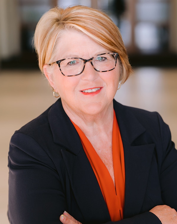 a woman wearing glasses and smiling at the camera