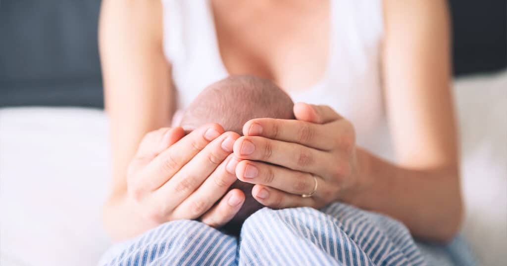 Photo of Mother Holding the Head of Her Newborn Baby